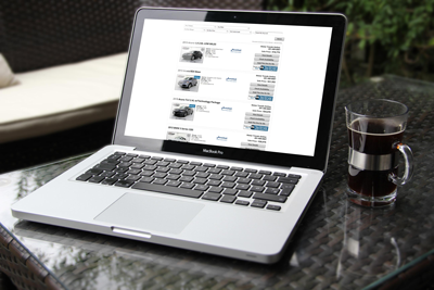 Laptop with car dealer website on the screen on a desk with a coffee mug.
